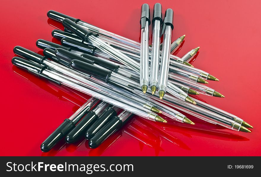 A close up of lots of black ballpoint pens on a red background. A close up of lots of black ballpoint pens on a red background