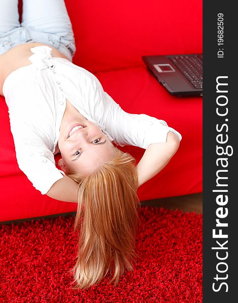 Attractive young woman lying on the sofa near the laptop. Attractive young woman lying on the sofa near the laptop