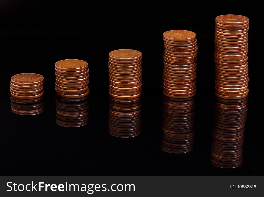 A pile of money coins with reflection over black