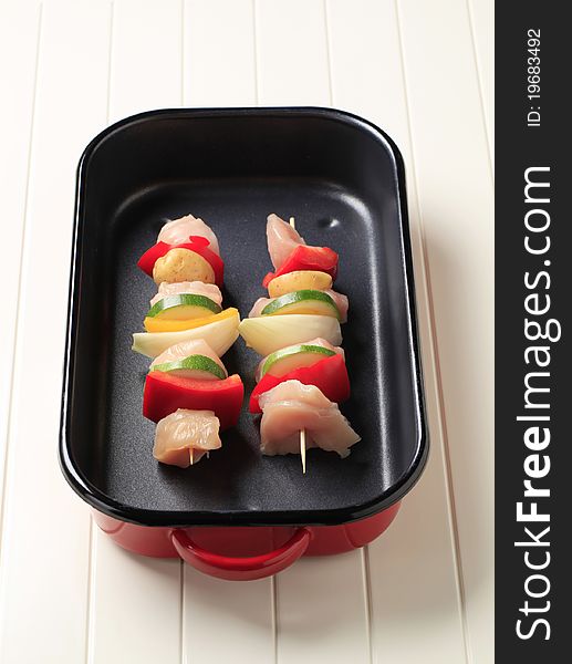 Raw chicken shish kebabs in a roasting pan