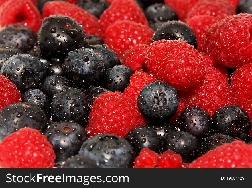 Fresh raspberries and blueberries with water drops