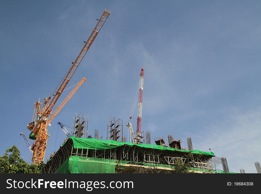 Crane and building construction on blue sky background.