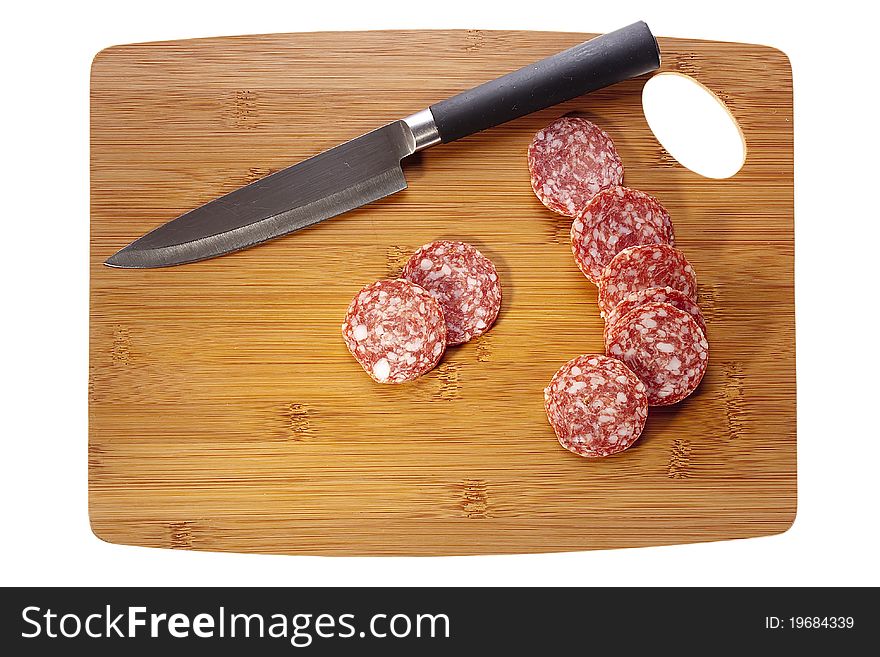 Sliced salami laying next to a knife on a brown cutting board. Sliced salami laying next to a knife on a brown cutting board.