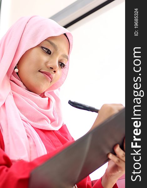 A young beautiful muslim girls writing on report file