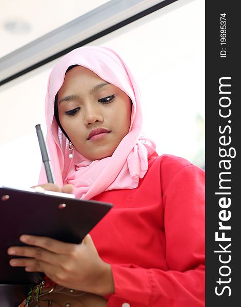 A young beautiful muslim girls writing on report file