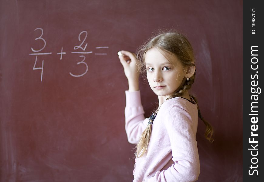 Young schoolgirl standing by the blackboard