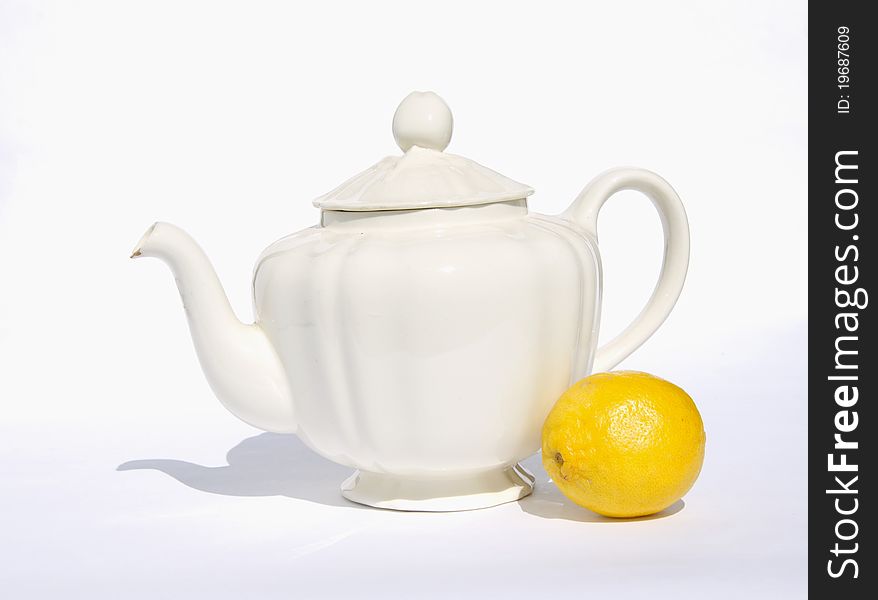 Still-life with white teapot and lemon on white background