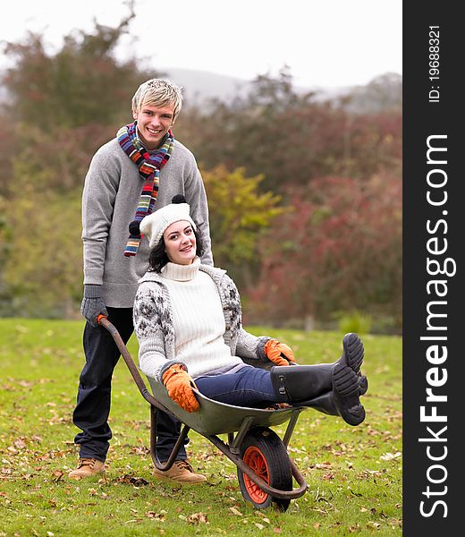 Young couple playing in wheelbarrow smiling at camera