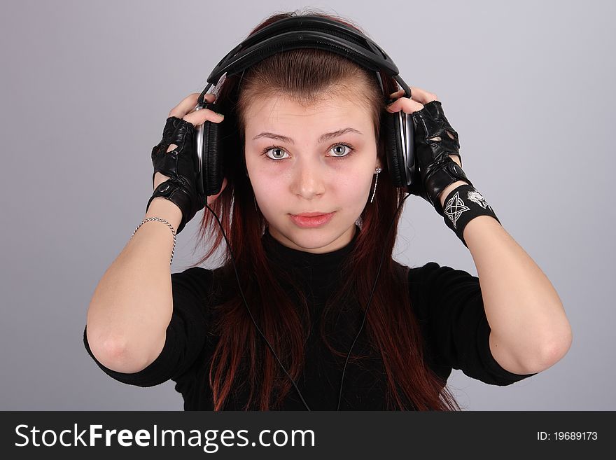 Portrait of the young charming girl with ear-phones and in black gloves. Portrait of the young charming girl with ear-phones and in black gloves