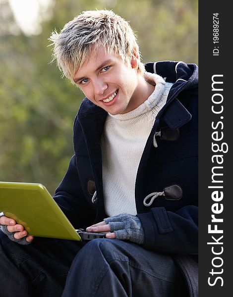 Young man with laptop computer smiling at camera