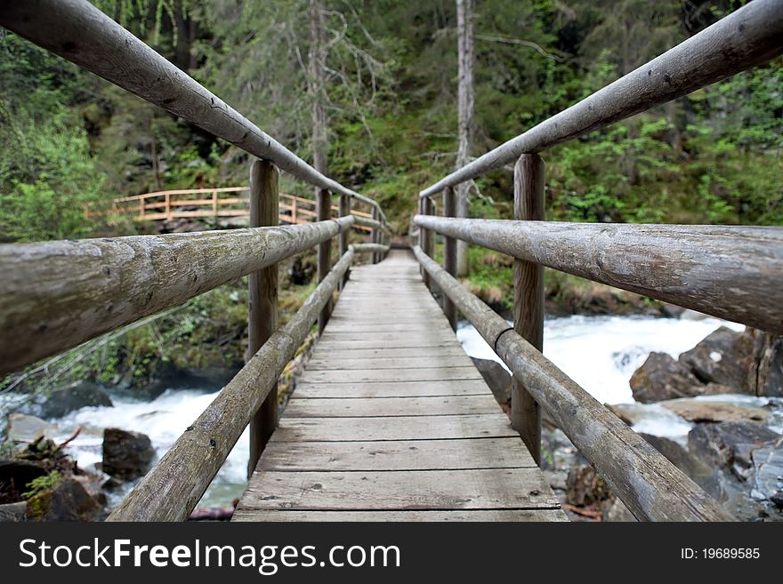 Wooden bridge across mountain river, Austrian Alps