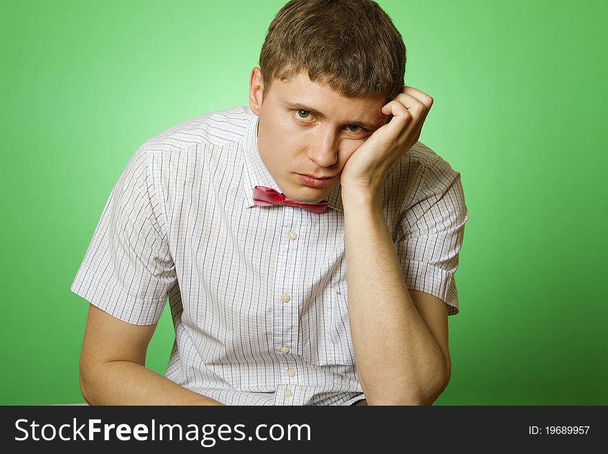 Handsome young man in a shirt with a green background sad at the camera. Handsome young man in a shirt with a green background sad at the camera.