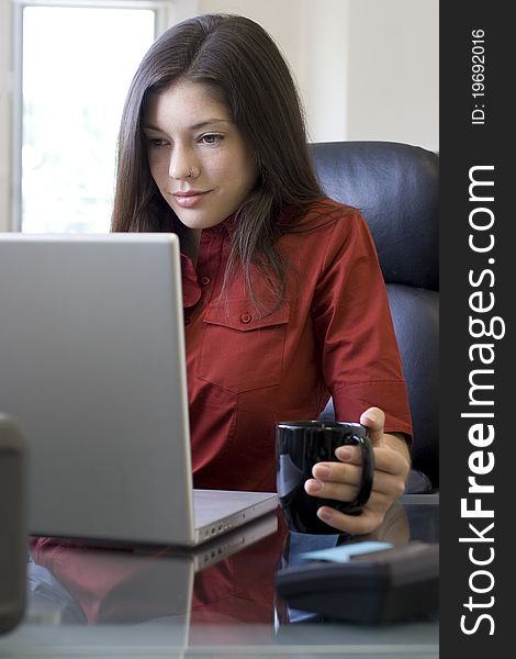 Young businesswoman with laptop surfing the web at her desk