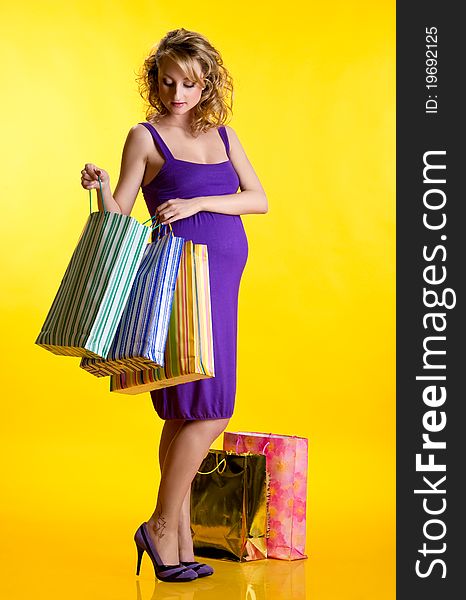 Beautiful pregnant woman looking inside shopping bags