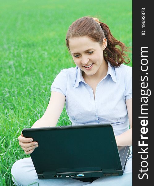 Girl sitting in the grass with laptop