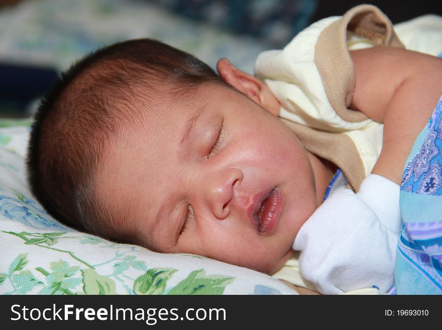 A newborn baby boy is sleeping deeply in his mother's arm. A newborn baby boy is sleeping deeply in his mother's arm.