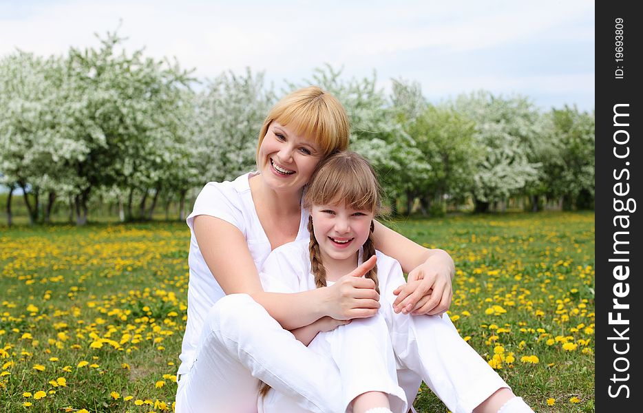 Happy girl and her mother in the spring park among flowers. Happy girl and her mother in the spring park among flowers