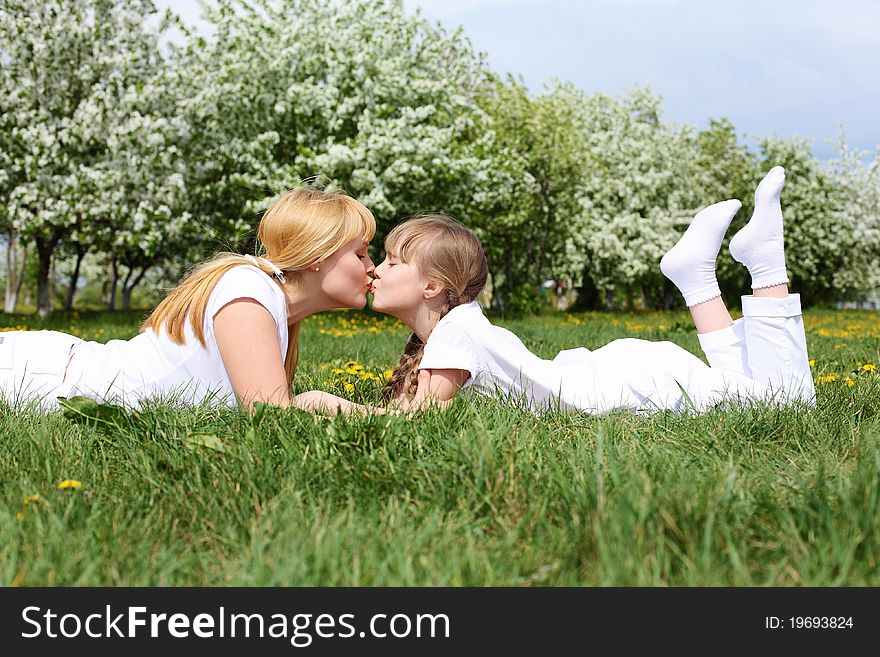 Happy girl and her mother in the spring park among flowers. Happy girl and her mother in the spring park among flowers