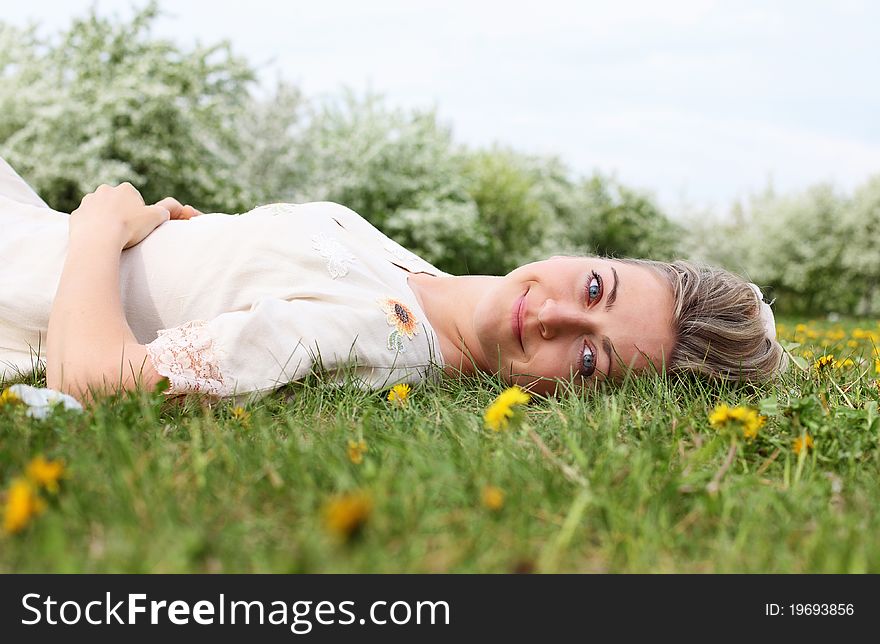 Young woman in spring park among flowers