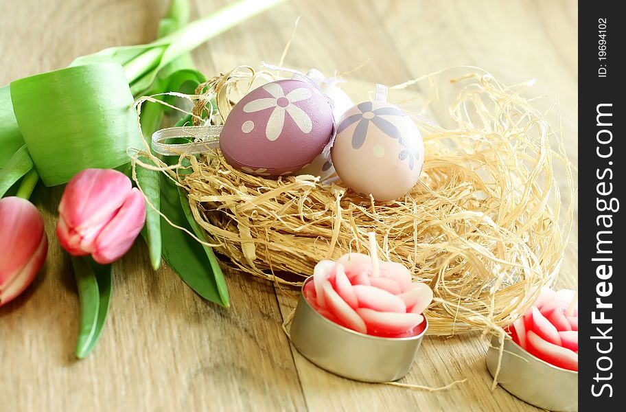 Easter eggs, tulips and candles on wooden boards