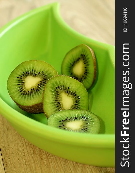 Kiwi in green bowl on wooden table