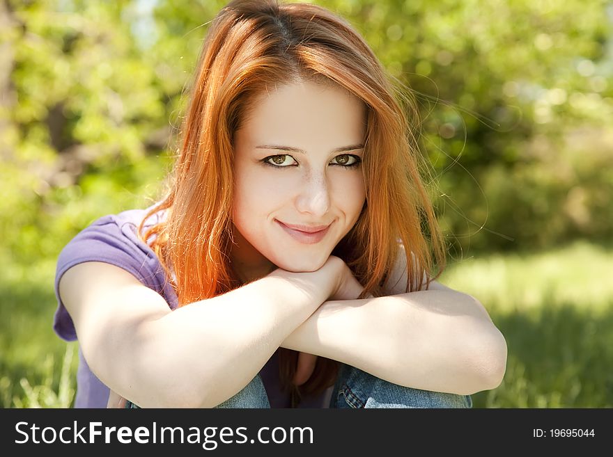 Beautiful redhead girl at the park in summer time.