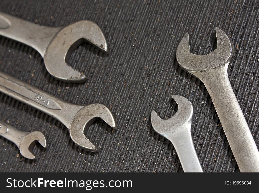 Set of used wrenches in a dirty black rubber mat