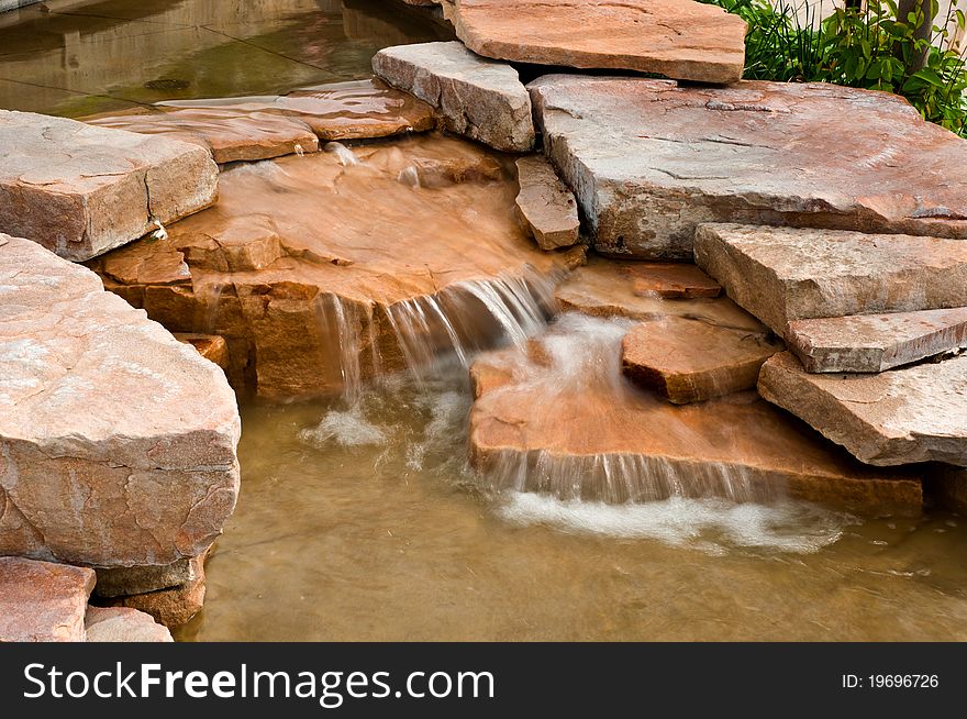 A waterfall with blurred water on red and brown rocks. A waterfall with blurred water on red and brown rocks