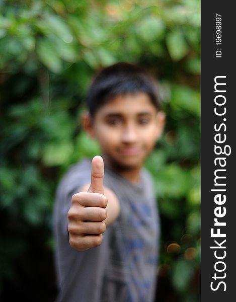 An handsome indian kid showing thumbs up for success