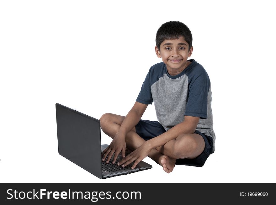 An handsome Indian kid having fun with laptop