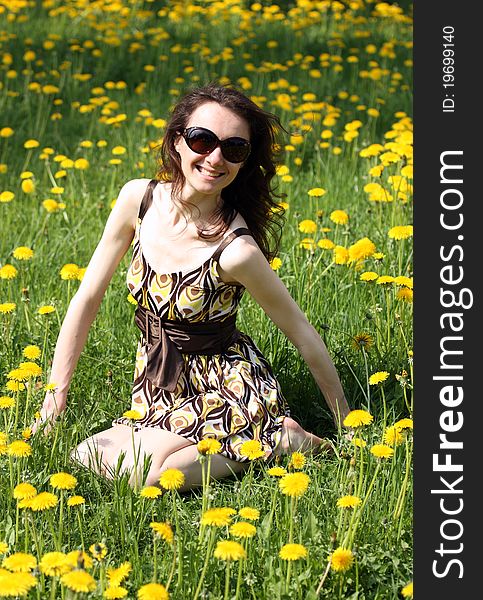 Happy young smiling woman enjoying the sun on a meadow full of yellow dandelions. Happy young smiling woman enjoying the sun on a meadow full of yellow dandelions