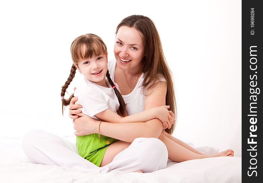 Beautiful young mother and her five year old daughter on the bed at home. Beautiful young mother and her five year old daughter on the bed at home