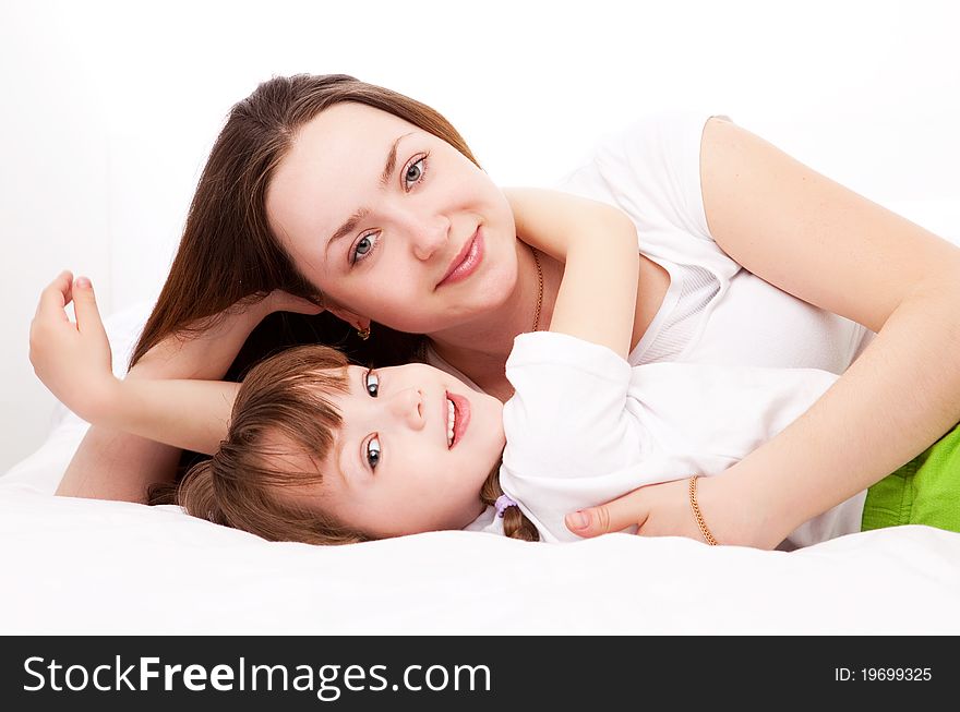 Beautiful young mother and her five year old daughter on the bed at home. Beautiful young mother and her five year old daughter on the bed at home