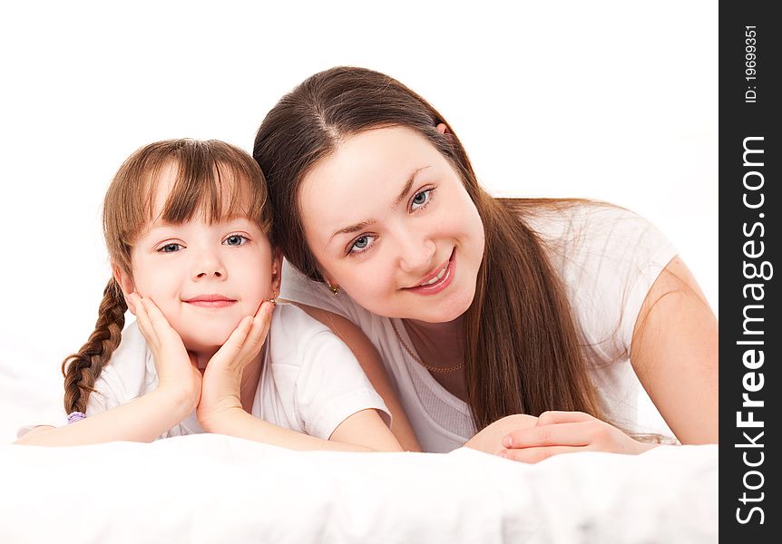 Beautiful young mother and her five year old daughter on the bed at home. Beautiful young mother and her five year old daughter on the bed at home