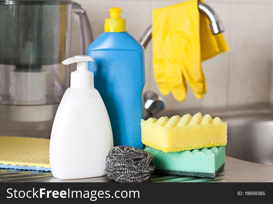 Bottles, sponges on foreground on kitchen