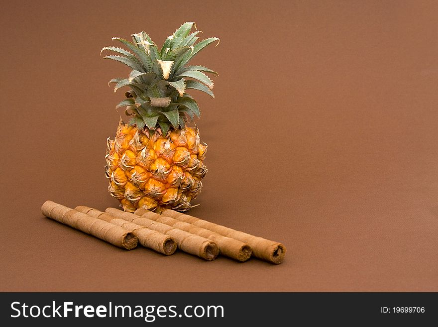 Baby pineapple and sweets on brown background. Baby pineapple and sweets on brown background