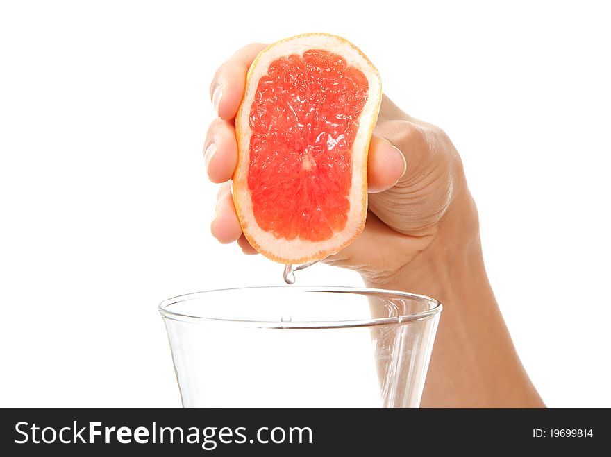 Hand squeezing red orange or grapefruit juice in glass isolated on a white background