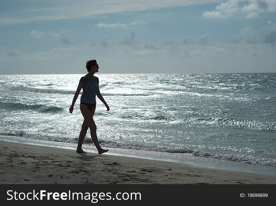 Woman silhouette on the beach walking