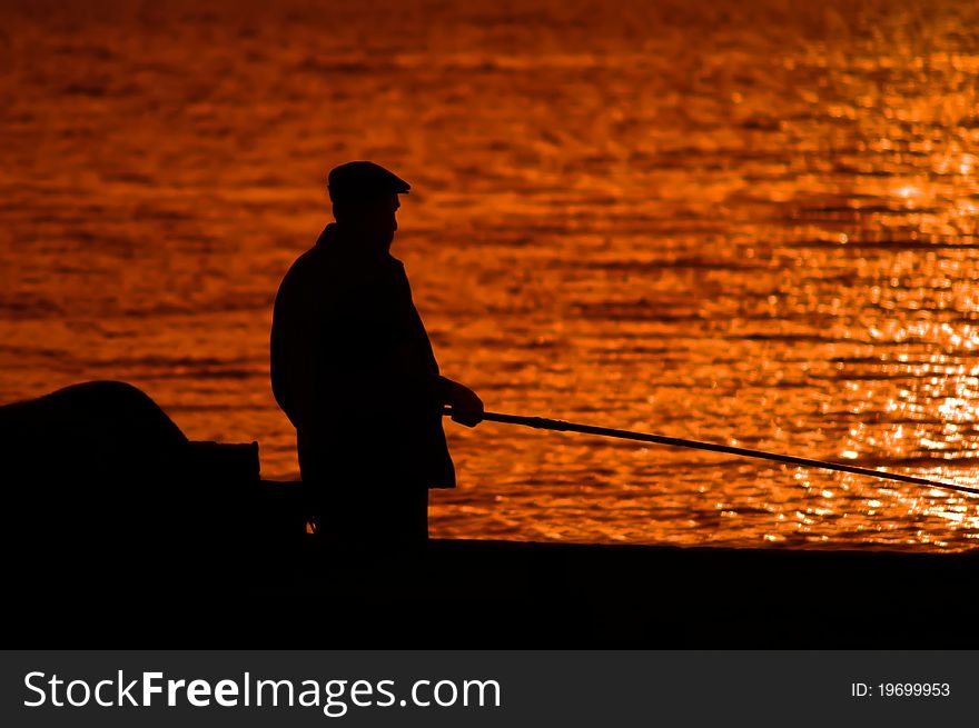 Man fishes on the sea before sunset. Man fishes on the sea before sunset.