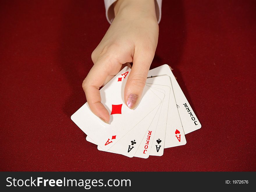 Two jokers and four aces - playing cards on red in human hand. Two jokers and four aces - playing cards on red in human hand