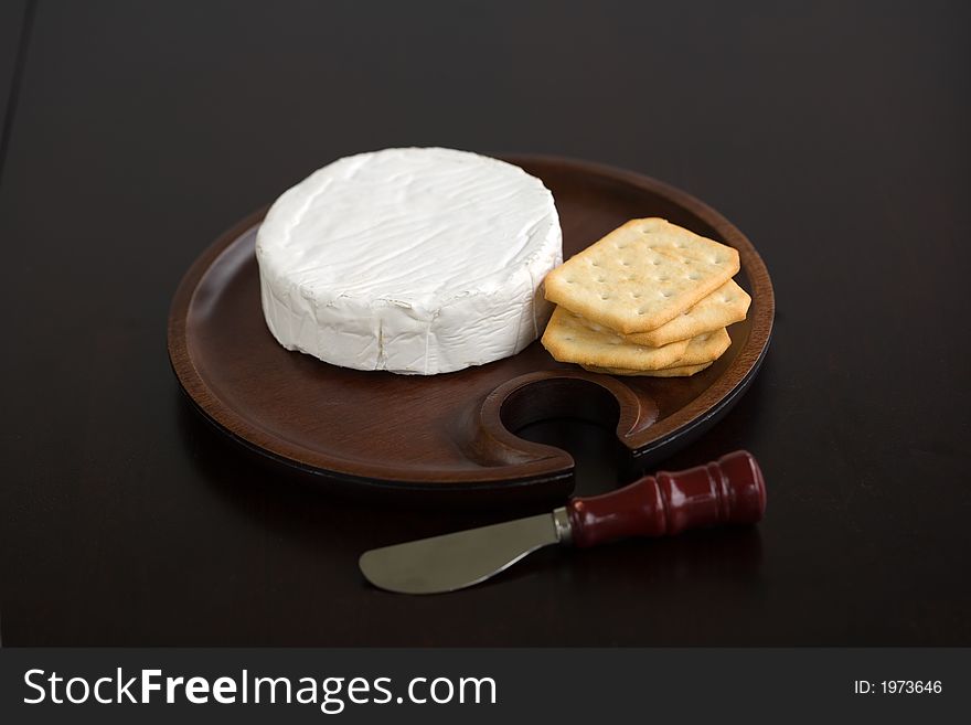 Brie and butter cracker on a wooden cheese plate with cheese knife. Brie and butter cracker on a wooden cheese plate with cheese knife