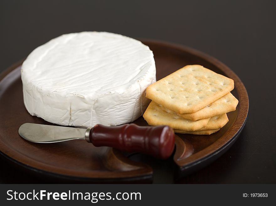 Brie and butter cracker on a wooden cheese plate with cheese knife. Brie and butter cracker on a wooden cheese plate with cheese knife