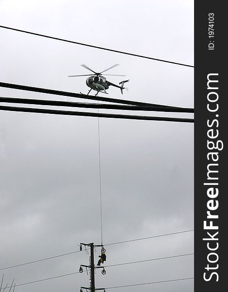 Workers hanging from helicopter wiring cables