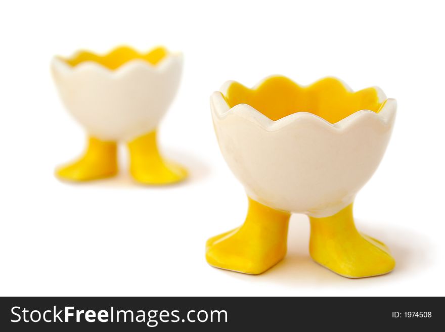 Two empty, funny egg holders waiting for their eggs. Shallow DOF with focus on the front of the front eggcup. Isolated on white background. Two empty, funny egg holders waiting for their eggs. Shallow DOF with focus on the front of the front eggcup. Isolated on white background.