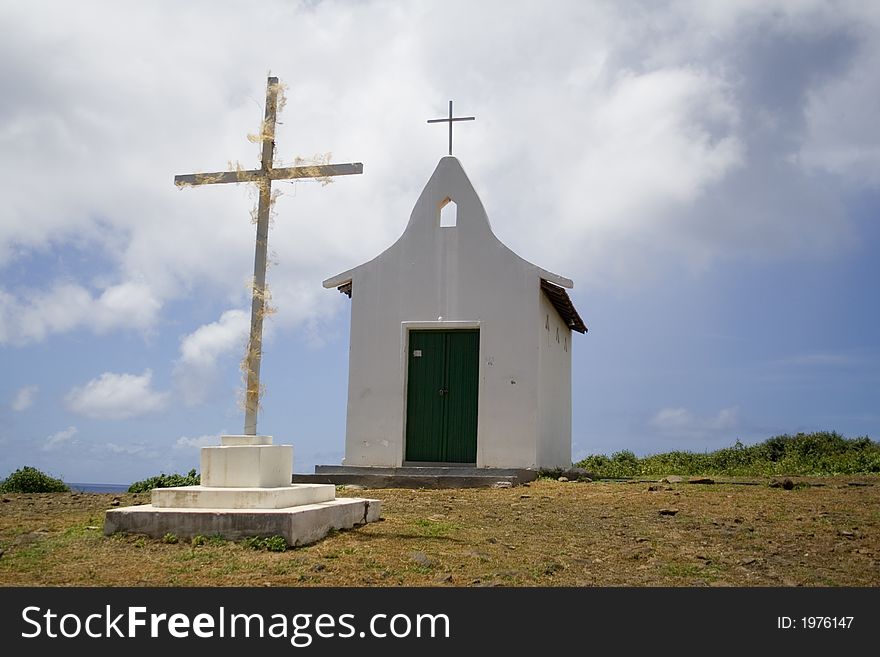 A small white chapel with green doors and a cross. A small white chapel with green doors and a cross.