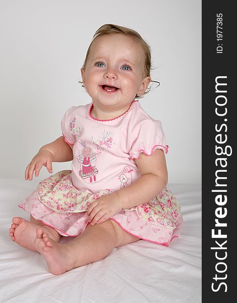 A little baby girl sitting in a pink dress. A little baby girl sitting in a pink dress