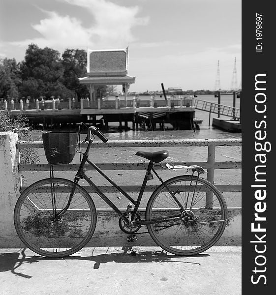 Old bicycle waiting at a quay along the Chao Praya river in Samut Prakan, Thailand. Black and white photo with background out of focus. Old bicycle waiting at a quay along the Chao Praya river in Samut Prakan, Thailand. Black and white photo with background out of focus.