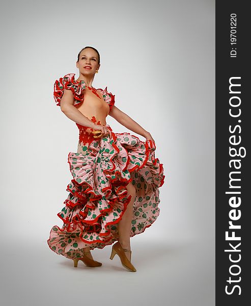Young woman dancing flamenco with castanets on gray background