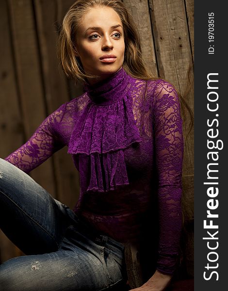 Fashion photo of young sensual woman in blue jeans and kombidress against wooden background