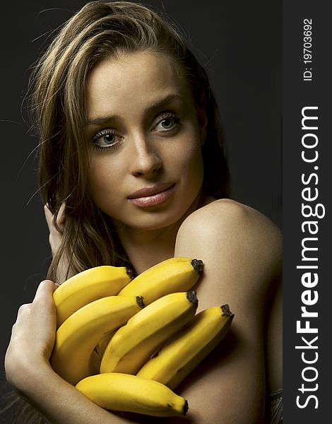 Beautiful young woman holding bananas